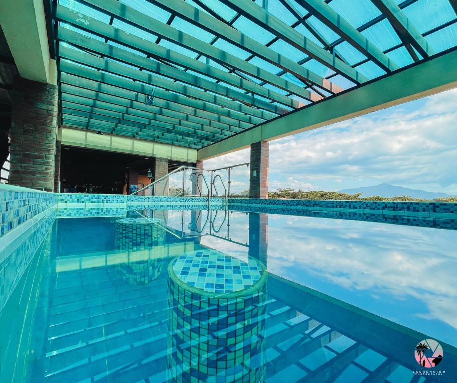 San NarcisoThe Palms Resort & Bar的一个带蓝色瓷砖和玻璃天花板的游泳池