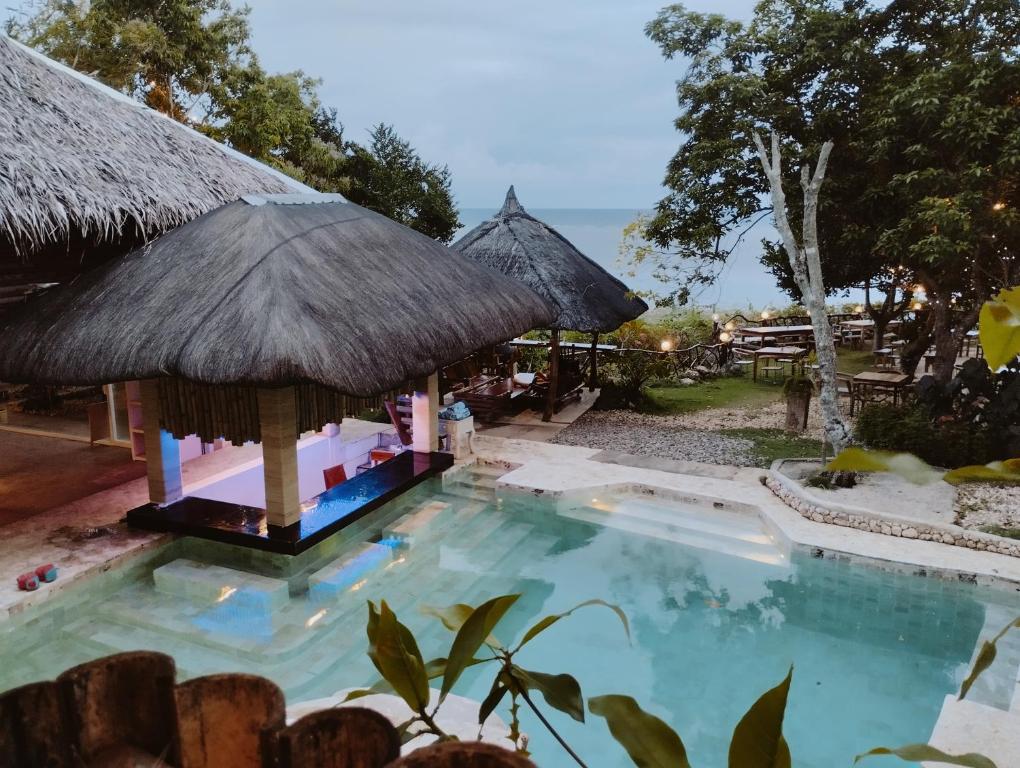 圣胡安Tahanan Resort的茅草屋顶度假村的游泳池
