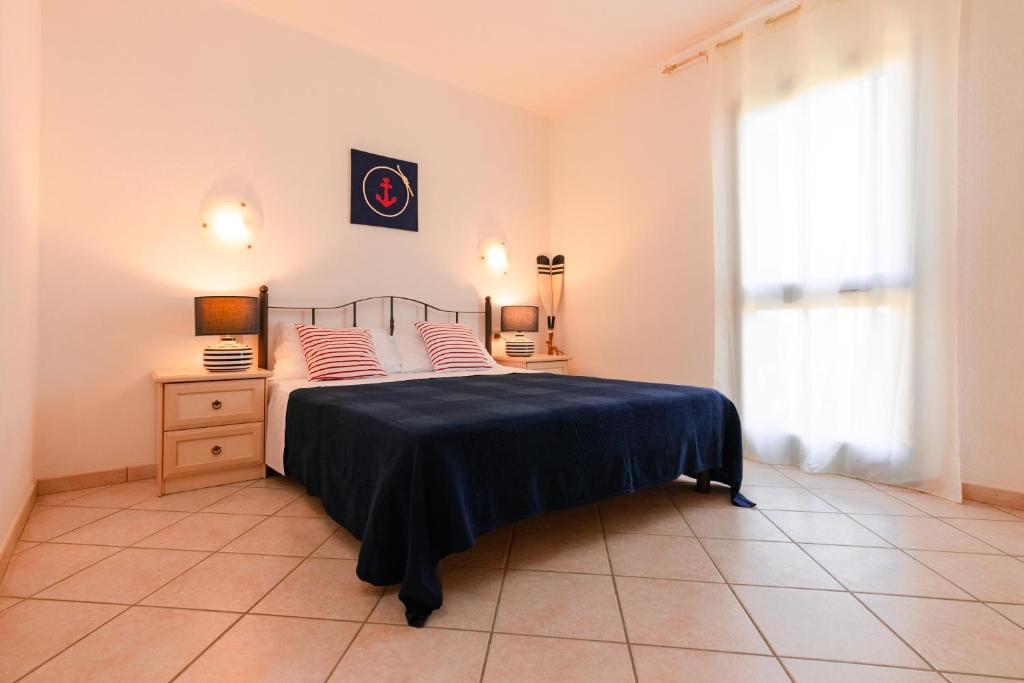 圣特奥多罗撒丁岛夏日丽卡普拉提公寓的一间卧室配有一张带蓝色毯子的床和窗户。