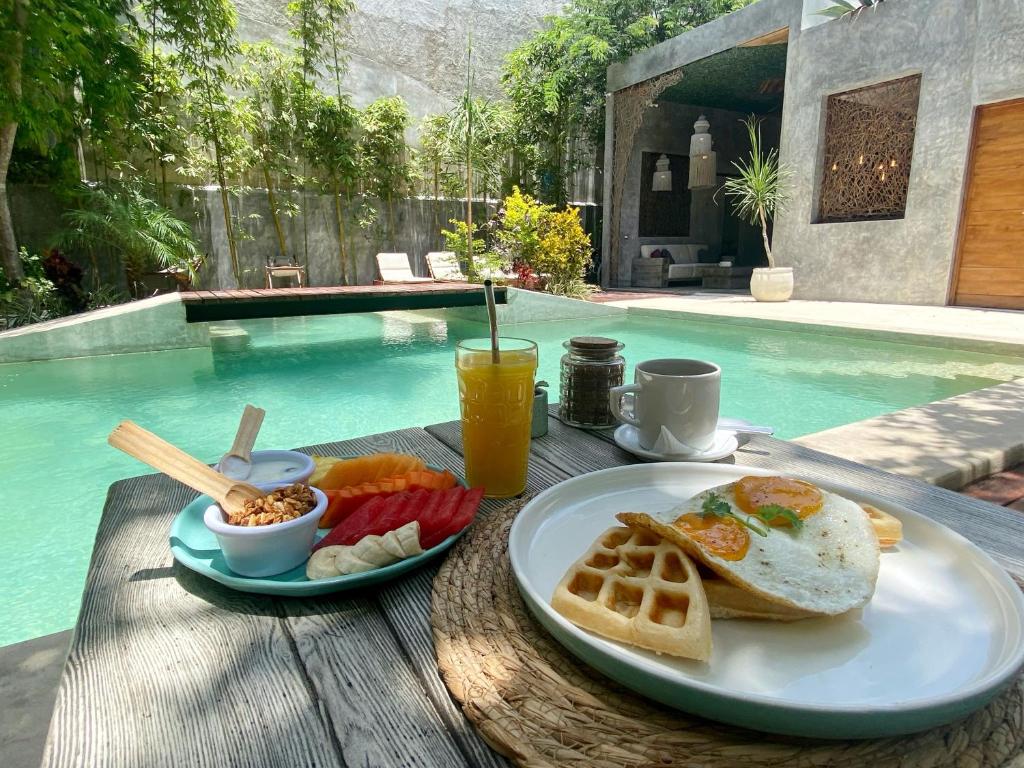 图卢姆Little Gem Hotel Tulum La Veleta的池畔餐桌上的早餐包括鸡蛋面包和水果