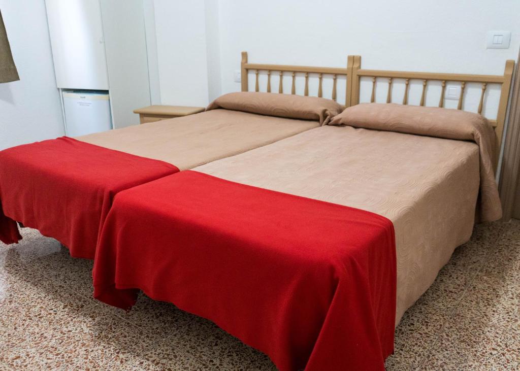 阿尔卡拉Pensión Alcalá的一间卧室配有两张带红毯的床