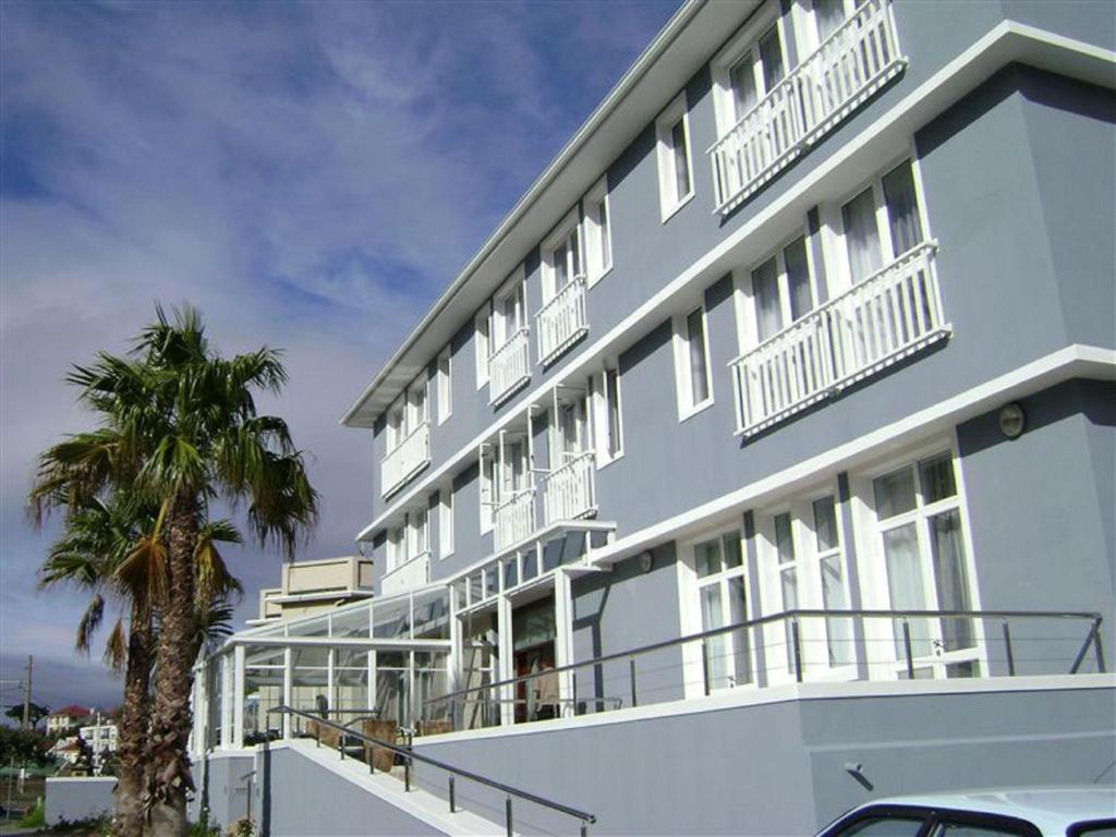 钓鱼镇卡尔德斯会议中心酒店的蓝色的建筑,设有白色的阳台和棕榈树
