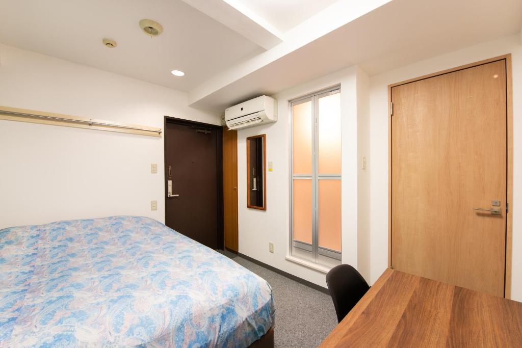 横滨Yokohama Sakuragicho Town Hotel的一间卧室配有一张床、一张桌子和一个窗户。
