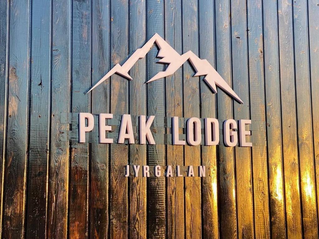 DzhergalanPeak Lodge Jyrgalan的木栅栏顶峰小屋的标志