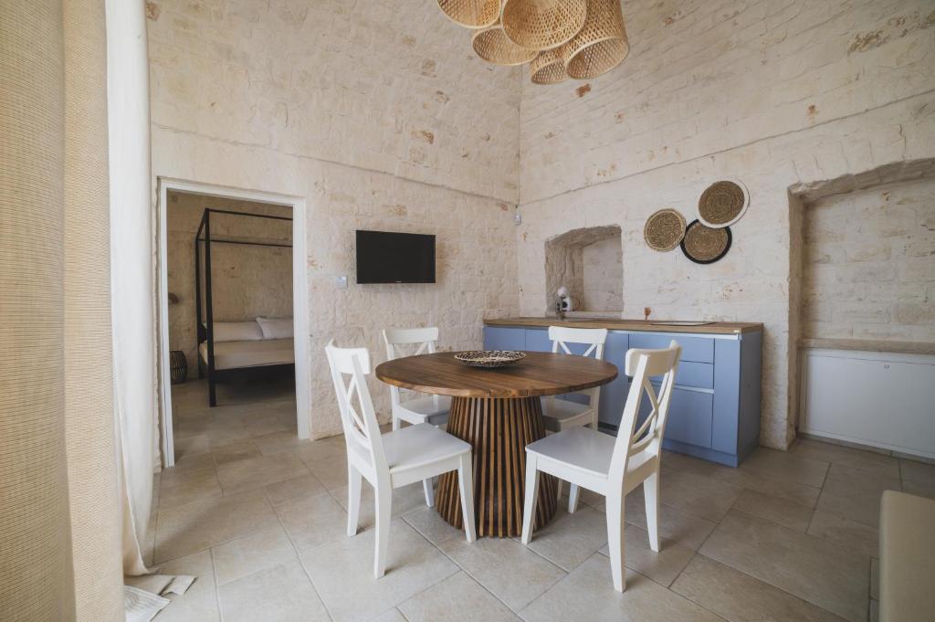 奇斯泰尼诺Dimorae Camà的一间带木桌和白色椅子的用餐室