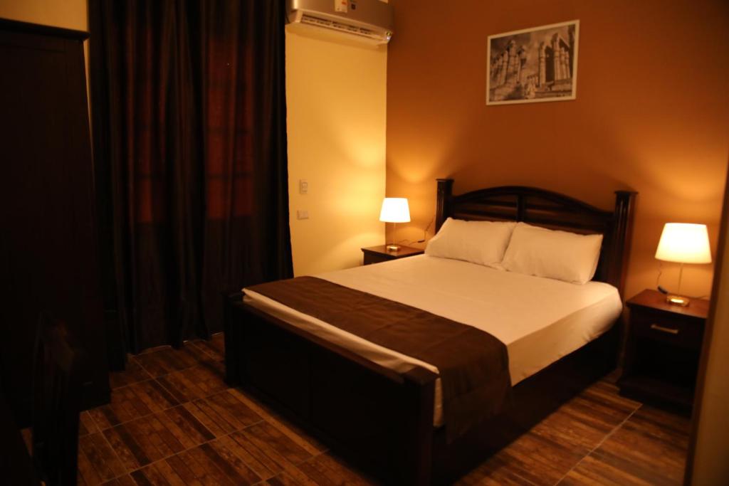 开罗Gresham Hotel的一间卧室配有一张带2个床头柜和2盏灯的床。