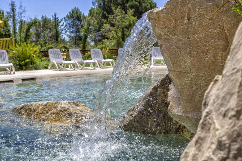 比比翁Bosco Canoro Bibione Resort的庭院里带椅子的游泳池中的喷泉