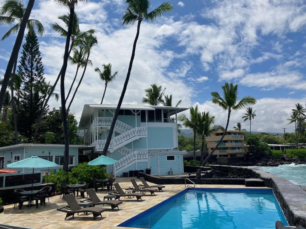 科纳Kona Tiki Hotel的一个带游泳池、椅子和棕榈树的度假村