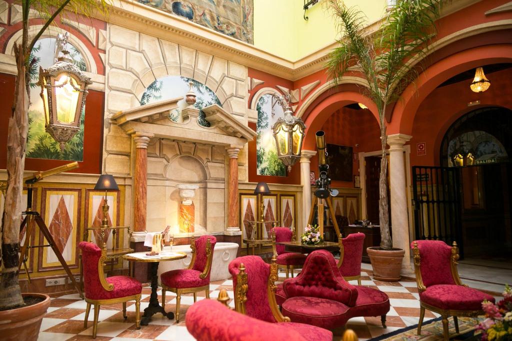 塞维利亚塞维利亚雅典娜酒店的大楼内带红色椅子和桌子的大堂