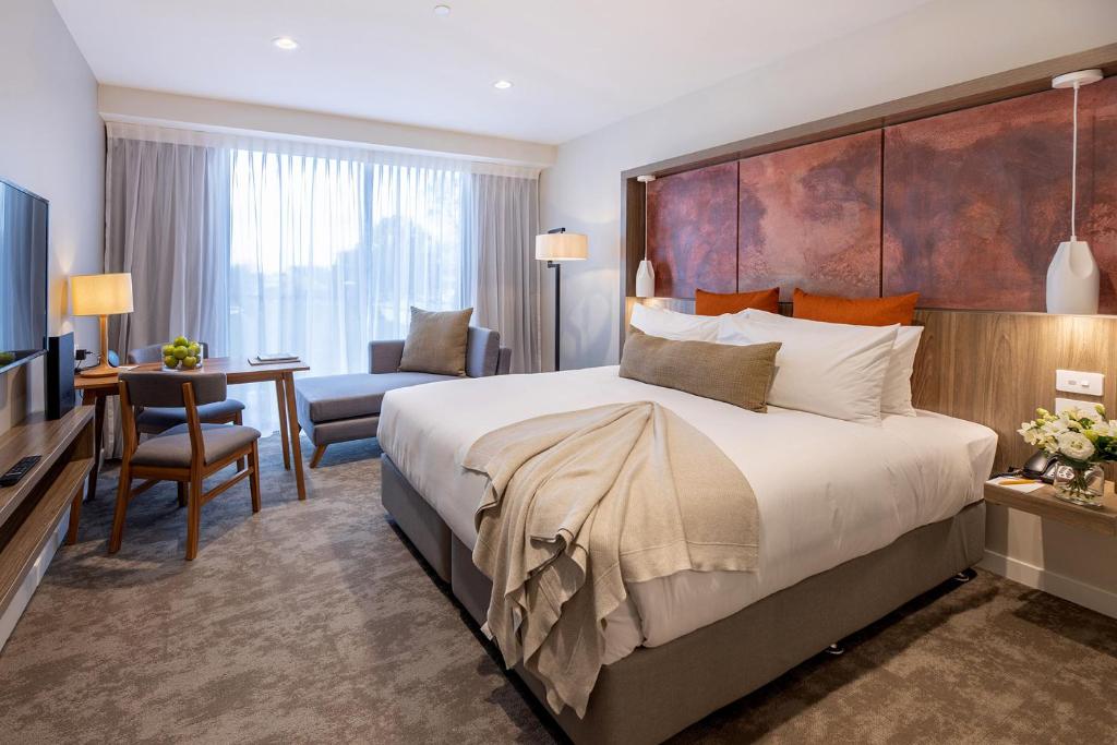 基督城Sudima Christchurch City的酒店客房设有一张大床和一张书桌。