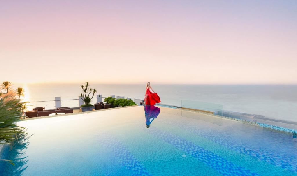 岘港海安海滩Spa酒店的站在游泳池边俯瞰大海的人