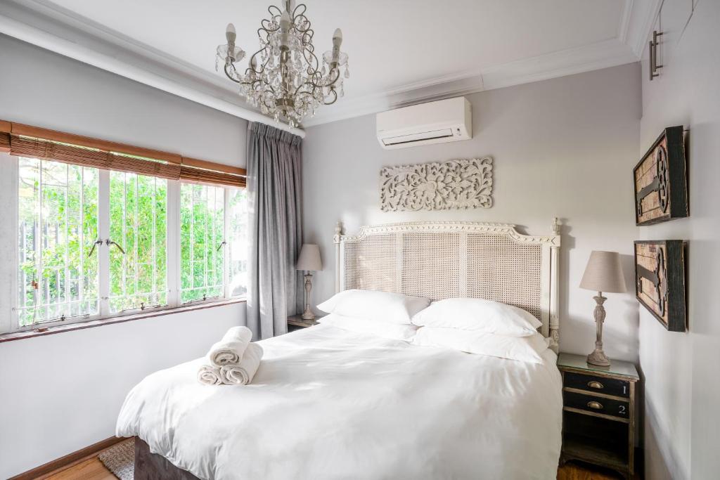 斯泰伦博斯Avemore Wag n Bietjie No 1的白色卧室配有一张带白色床单和吊灯的床
