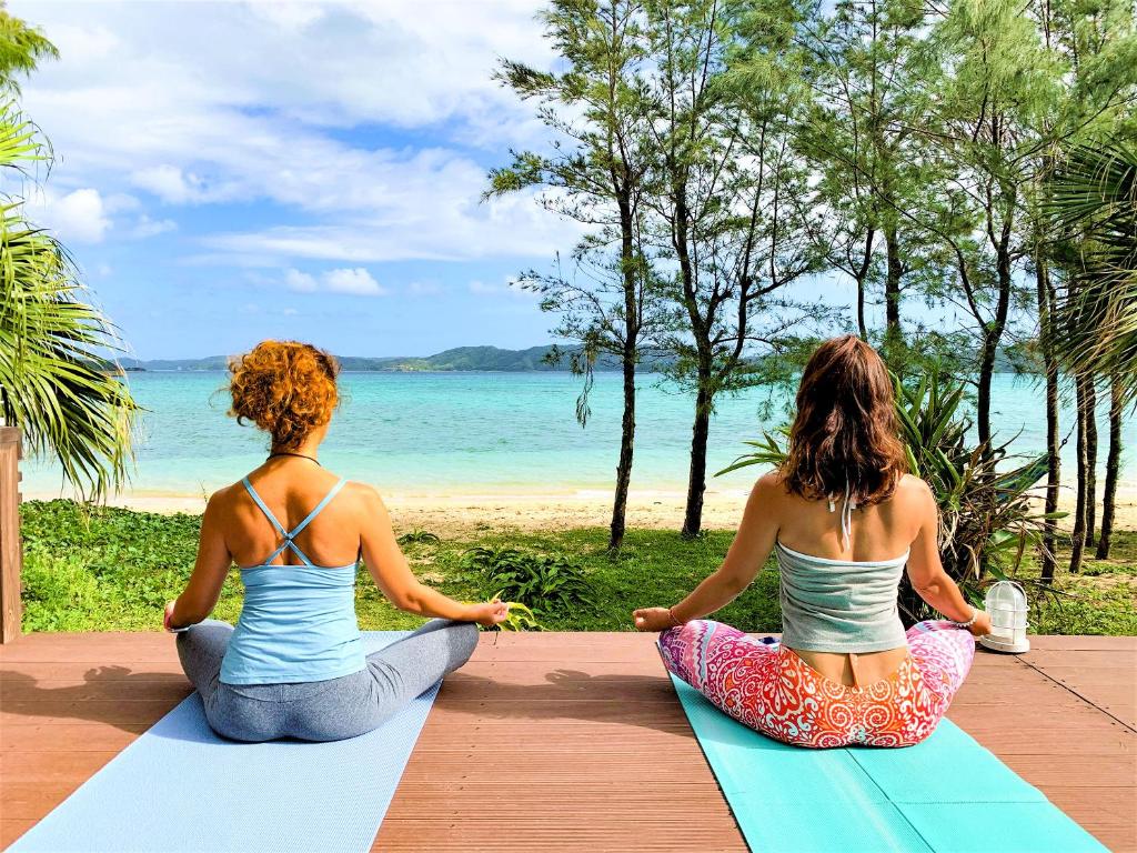 奄美Le Grand Bleu的两个女人坐在海滩上做瑜伽姿势