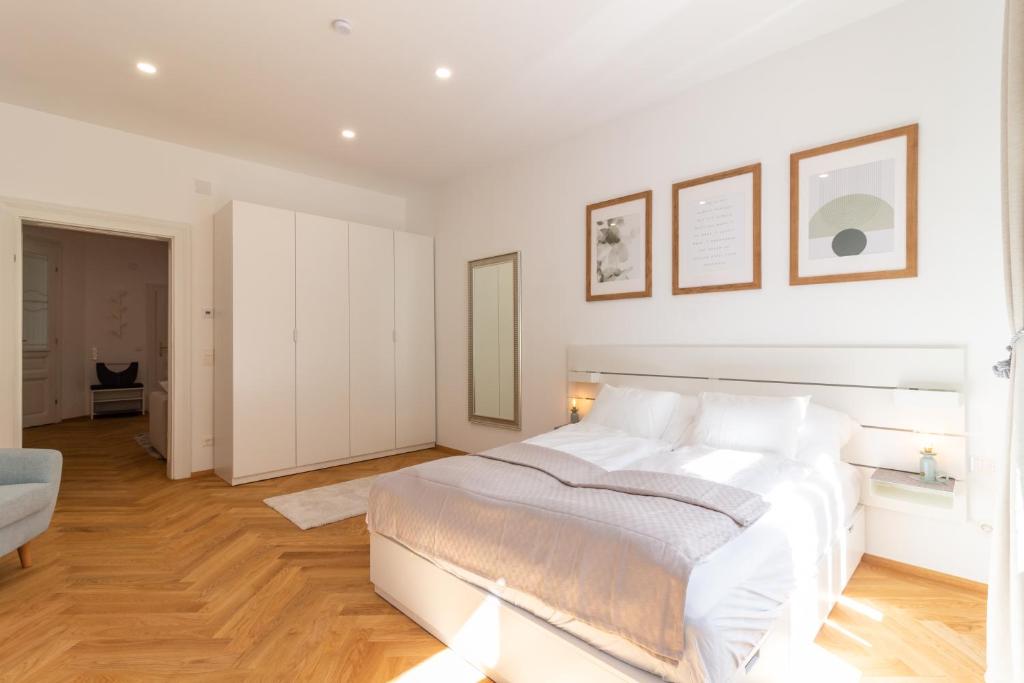 维也纳Vienna City Apartment的白色的卧室设有一张白色的大床和木地板