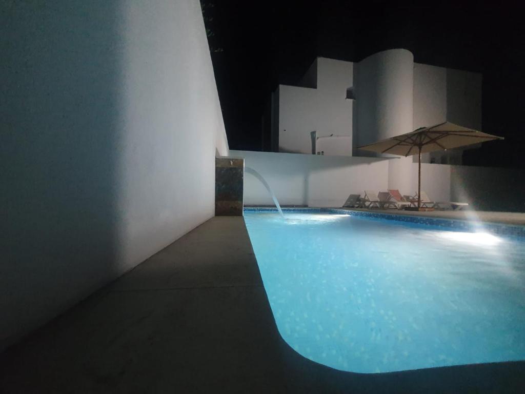 阿格希尔Villa de luxe avec piscine sans vis à vis Midoun的夜间游泳池,带遮阳伞