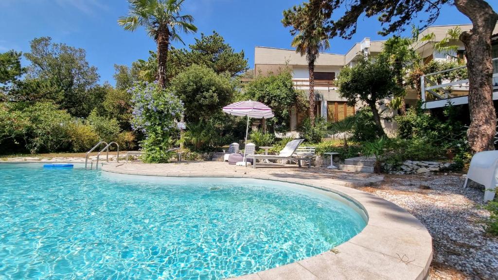 杜伊诺Villa Duino Trieste Reception的庭院内一个带遮阳伞和椅子的游泳池