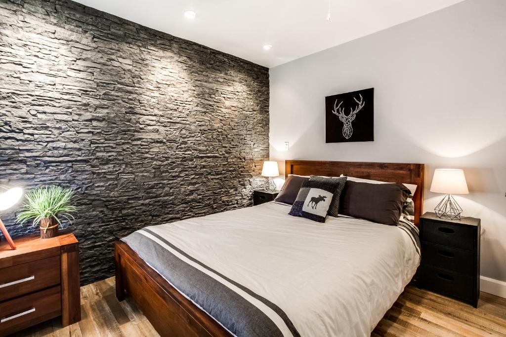 蒙特朗布朗Le Villageois by Gestion ELITE的一间卧室设有一张床和石墙