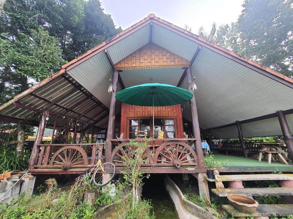 Ban Pak NamBaan Thabthong Homestay (บ้านทับทอง โฮมสเตย์)的一座桥上带绿伞的建筑