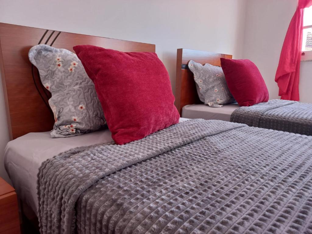 维塞乌Studios Rossio的一间卧室配有两张带红色和紫色枕头的床