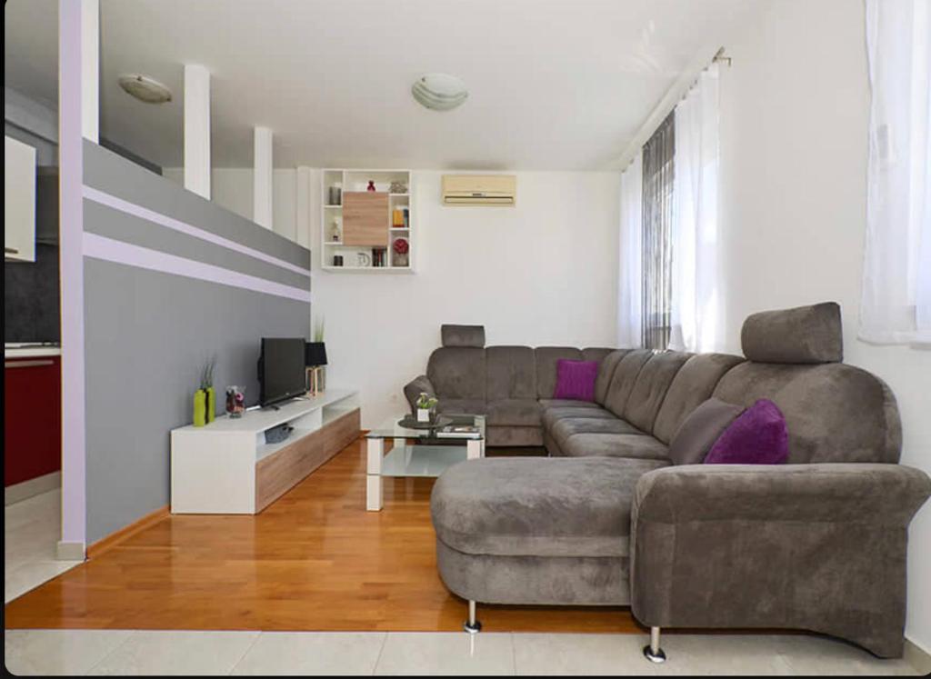珀德垂那Apartment Charlie的客厅配有灰色沙发和紫色枕头