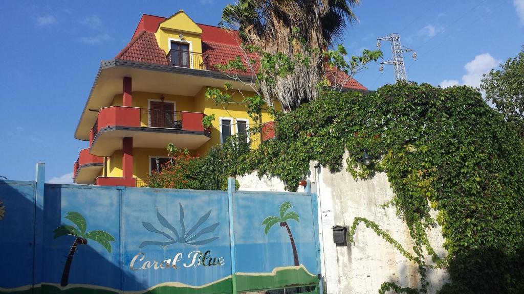 布里亚蒂科珊瑚蓝住宿加早餐旅馆的围栏后面的黄色和红色建筑