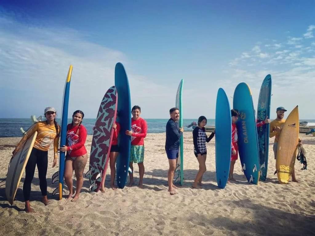 圣玛尔塔HOSTAL Estrellas del tayrona playa的一群人站在海滩上,拿着冲浪板