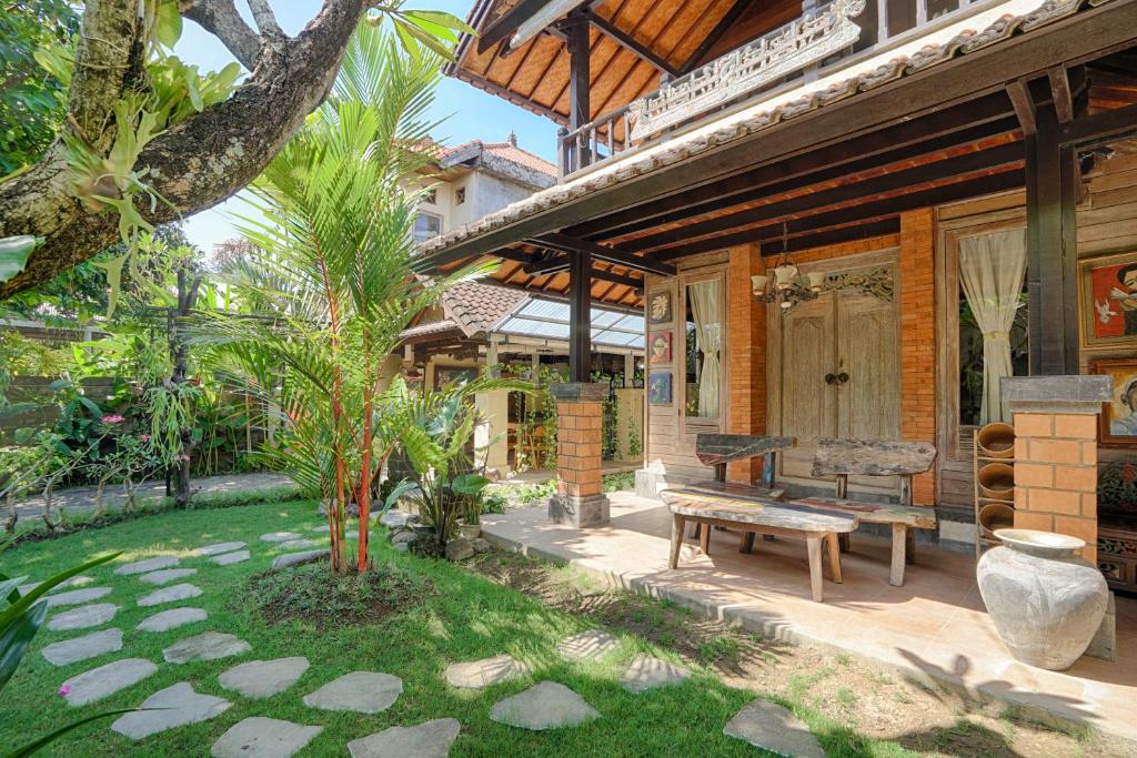 登巴萨Katang - Katang Guest House的一个带长凳和树的庭院