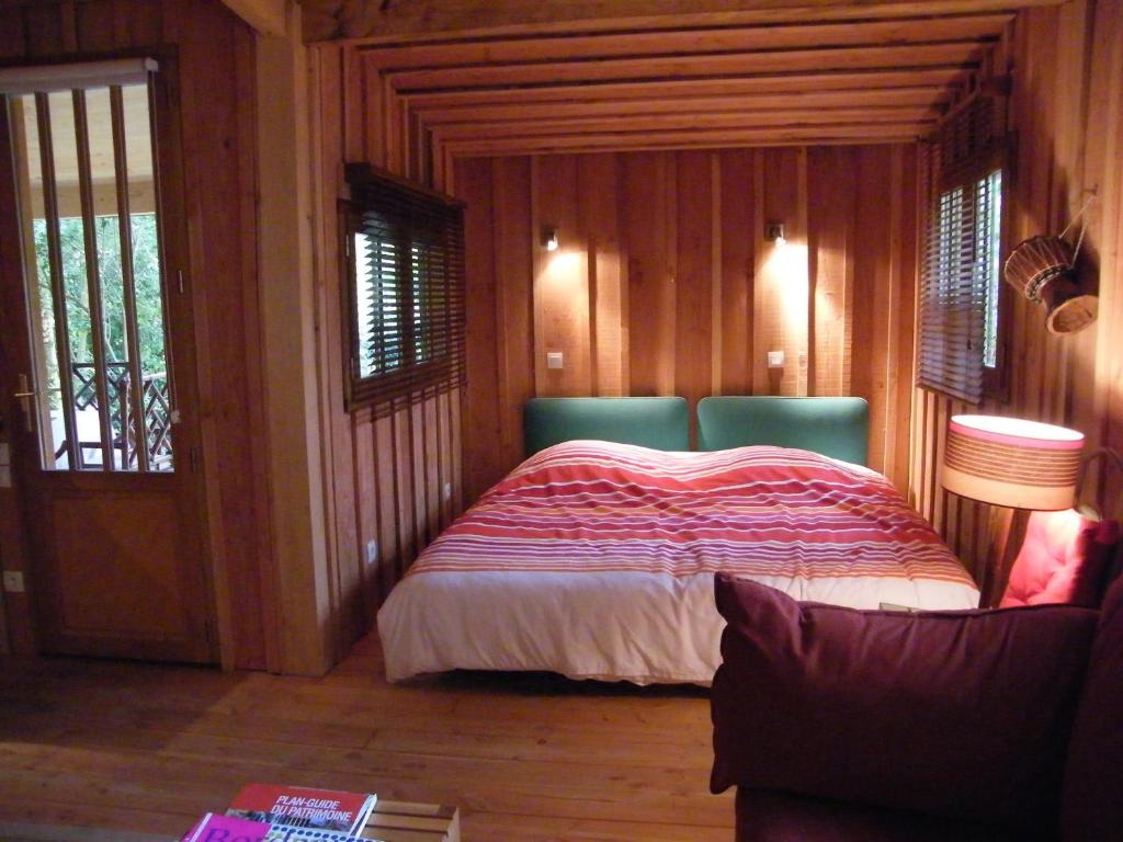 波尔多独特度假屋的卧室配有一张床铺,位于带木墙的房间内