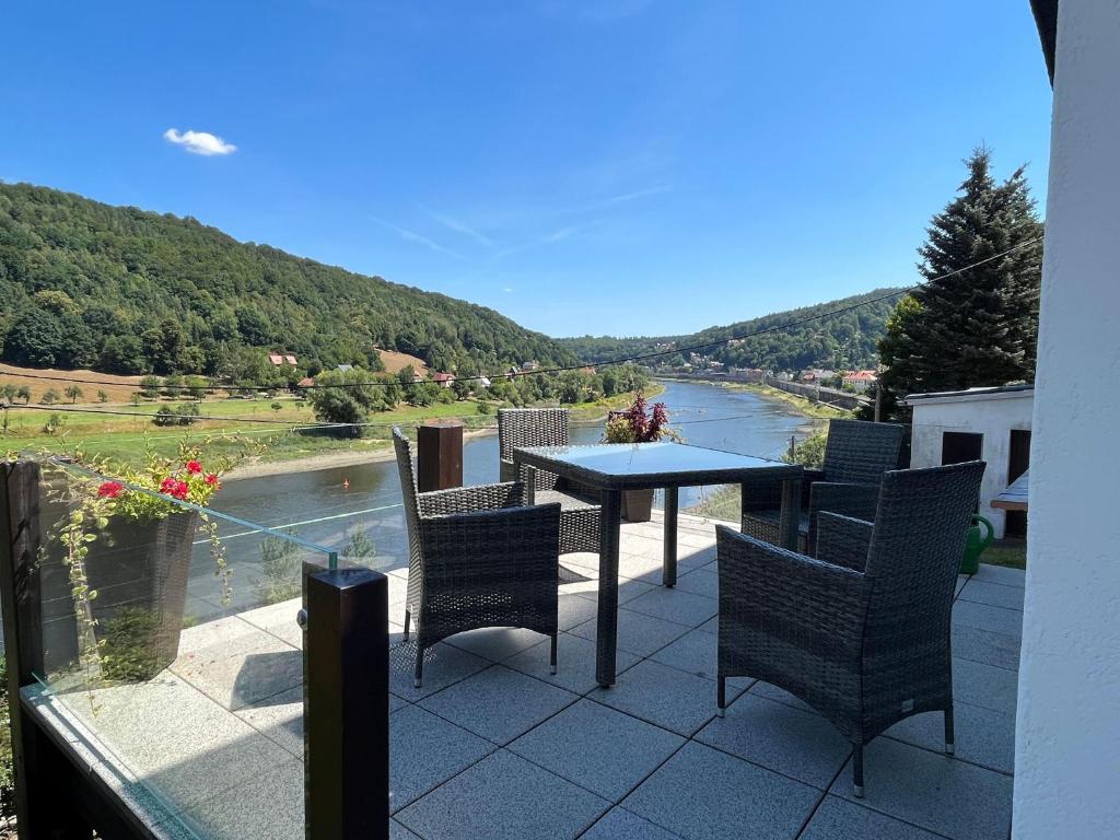 柯尼希施泰因易北Saechsische-Schweiz-Ferienhaus-Wohnung-2-mit-hervorragendem-Panoramablick-ueber-das-Elbtal的庭院配有桌椅,俯瞰着河流