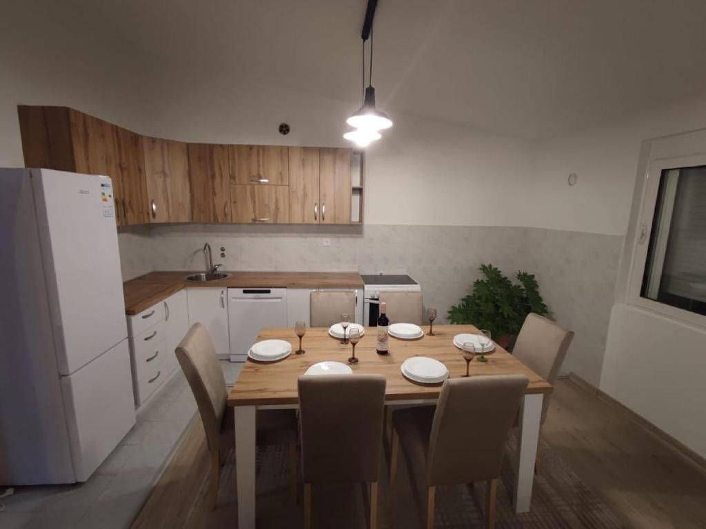 巴尔Guest House Tomba的厨房配有带椅子的木桌和白色冰箱。