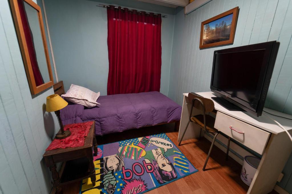 特木科Hostal Sol Temuco的一间小卧室,配有紫色的床和一台平面电视
