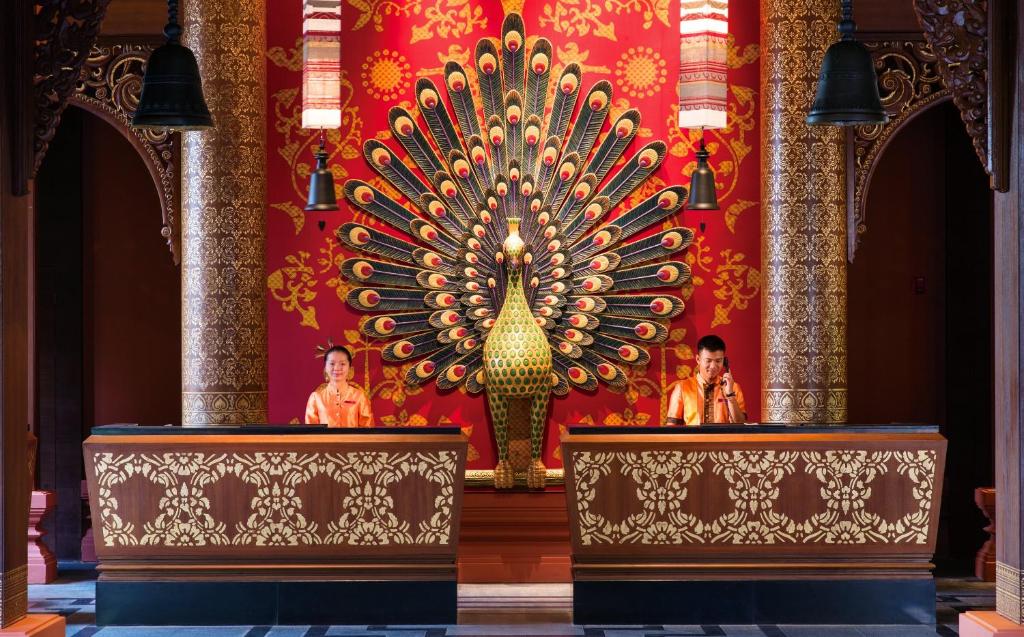 景洪市西双版纳洲际度假酒店的一座有两个人的寺庙,在红墙前
