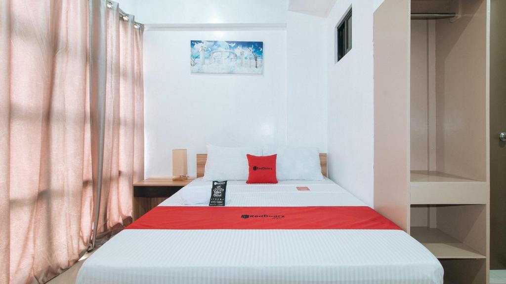 伊洛伊洛RedDoorz Near Iloilo International Airport的一间卧室配有一张红色枕头的床