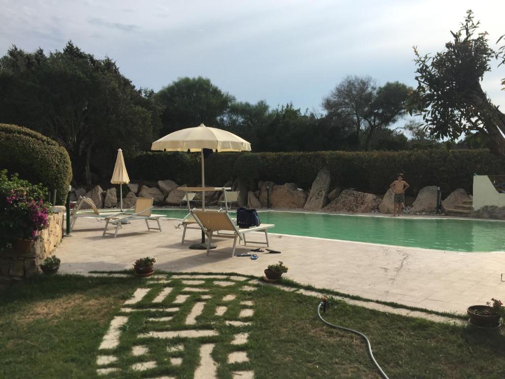 阿比亚多利green park cala di volpe的一个带遮阳伞和两把椅子及一张桌子的游泳池