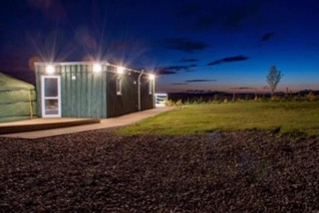 TurriffColourful Mongolian Yurt enjoy a new experience的一座绿色的小建筑,晚上有灯
