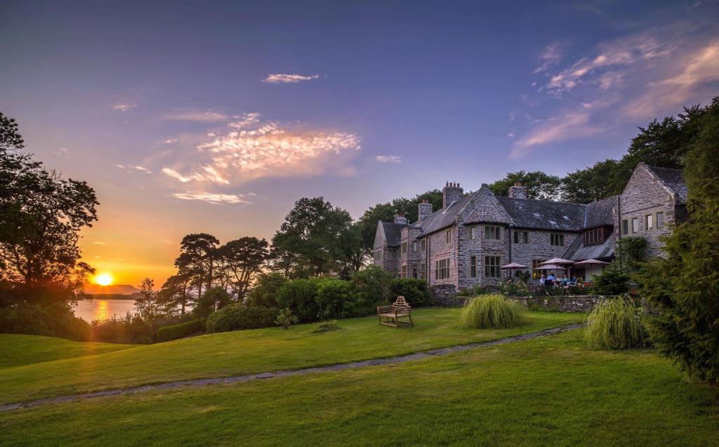 基洛格林Ard na Sidhe Country House Hotel的草坪上的大型房屋,背面是日落