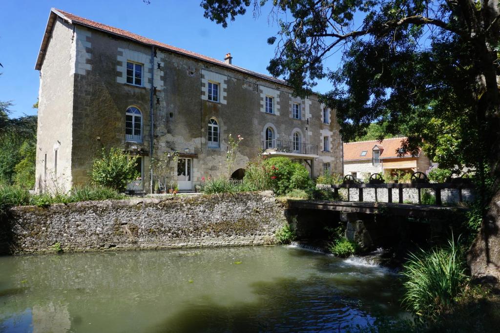NazellesLe Moulin de Moquesouris - Chambres d'hôtes et table d'hôte的水体旁的古老石头建筑