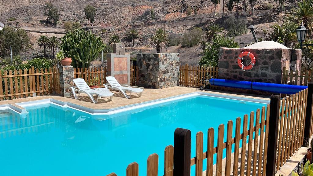 圣卢西亚casa rural LA LIMERA con piscina privada的围栏旁带两把椅子的游泳池