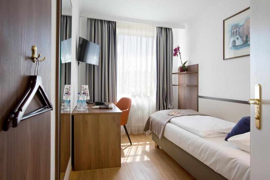 慕尼黑Hotel Aurbacher Hof GmbH的配有一张床和一张书桌的酒店客房