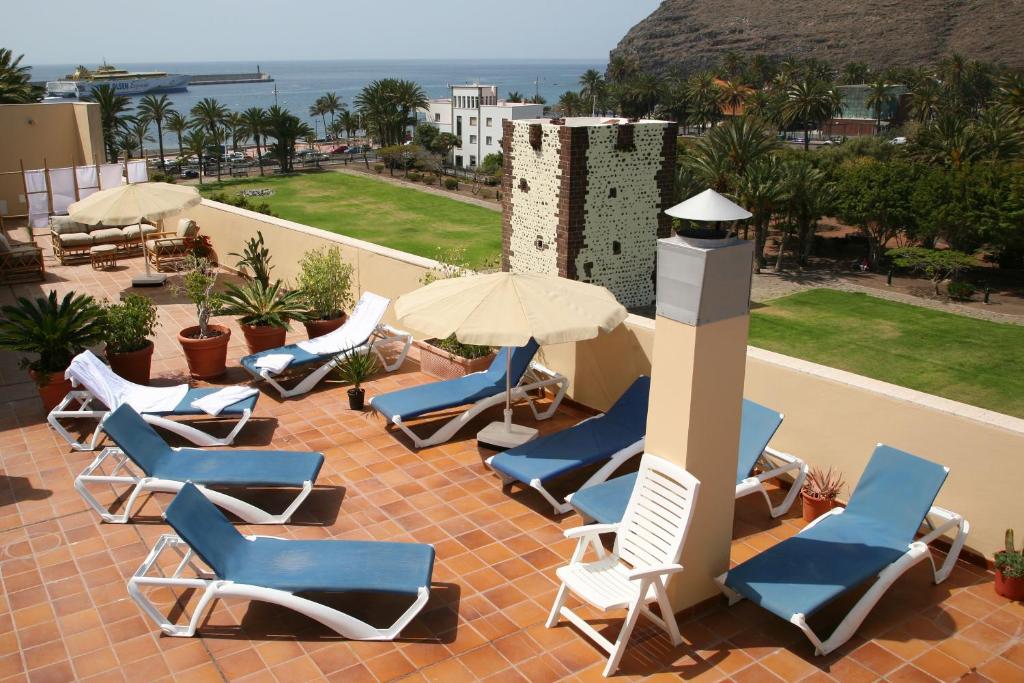 戈梅拉岛圣塞瓦斯蒂安托雷德孔德酒店的庭院里摆放着一组椅子和遮阳伞