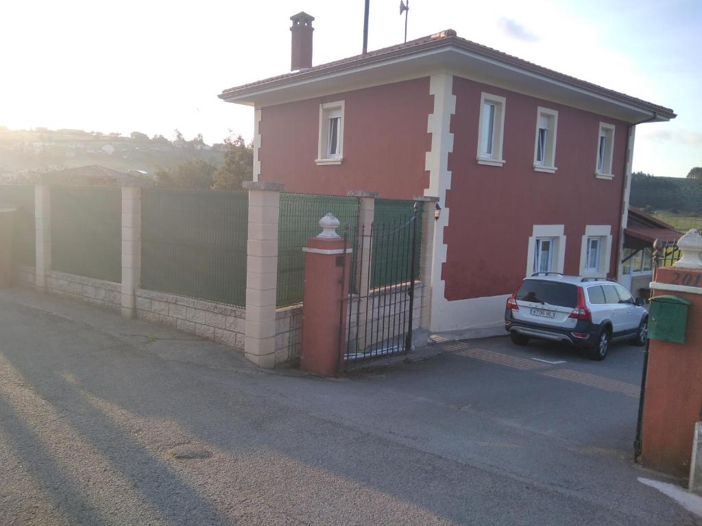 MonteCasa Bayona的一座红色的房子,上面有栅栏,前面有一辆汽车