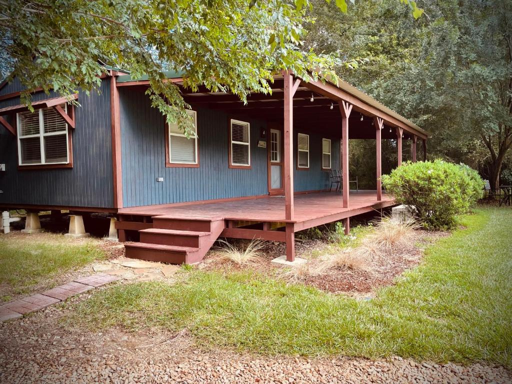 SummitCabin 3 - Modern Cabin Rentals in Southwest Mississippi at Firefly Lane的一座蓝色的小房子,在院子里设有门廊