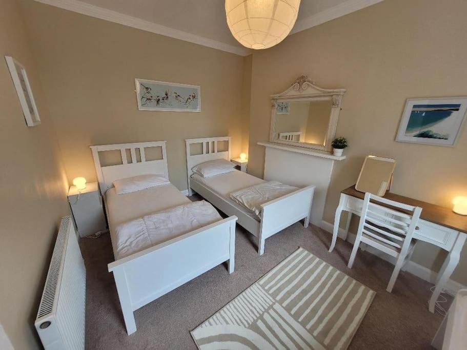 莫法特Character cottage in centre of Moffat的一间卧室配有两张床、一张桌子和一面镜子