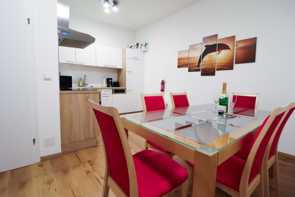 维也纳CozyNite Premium Apartment Schönbrunn 1的厨房以及带玻璃桌和红色椅子的用餐室。