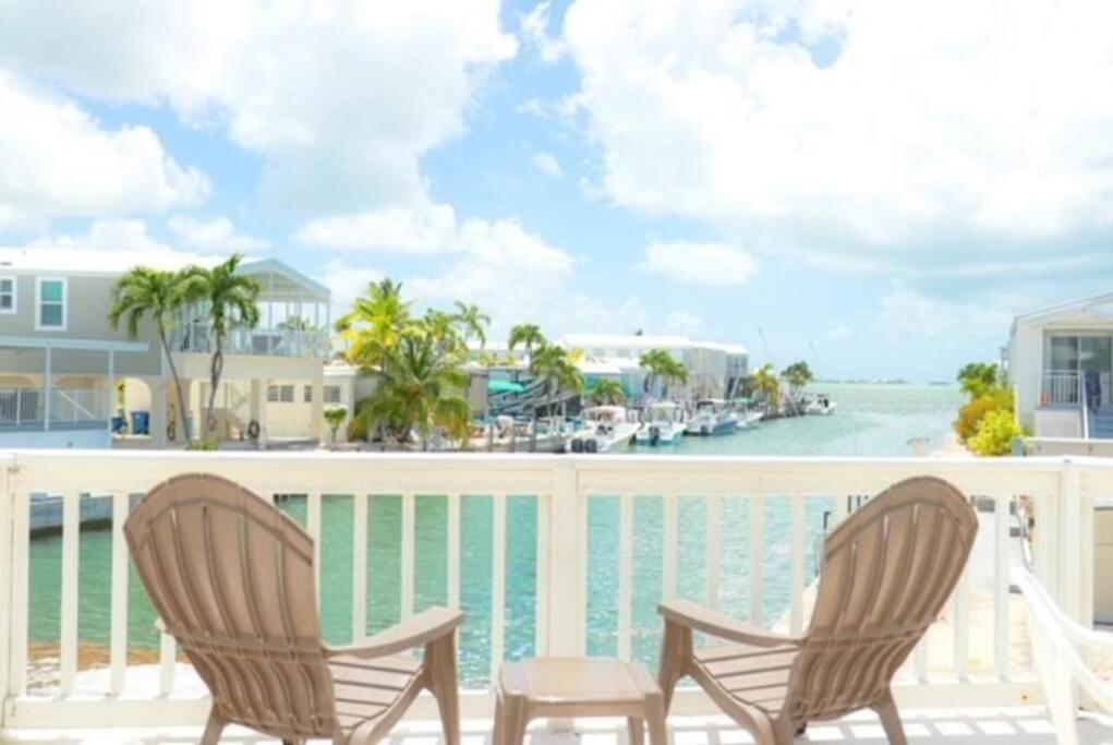 Cudjoe KeyIsland Oasis ~ YOUR Paradise Awaits!的俯瞰水面的阳台配有两把椅子和一张桌子