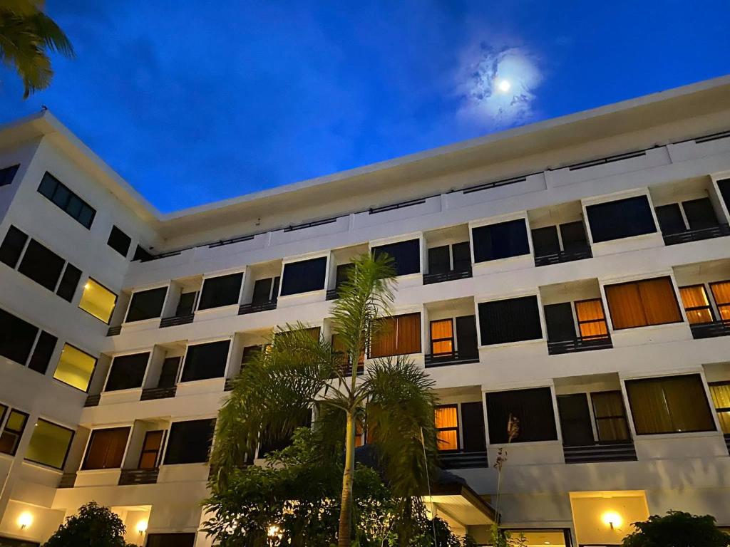 Chai BadanNaraigrand Hotel (โรงแรมนารายณ์แกรนด์)的一座白色的建筑,前面有棕榈树