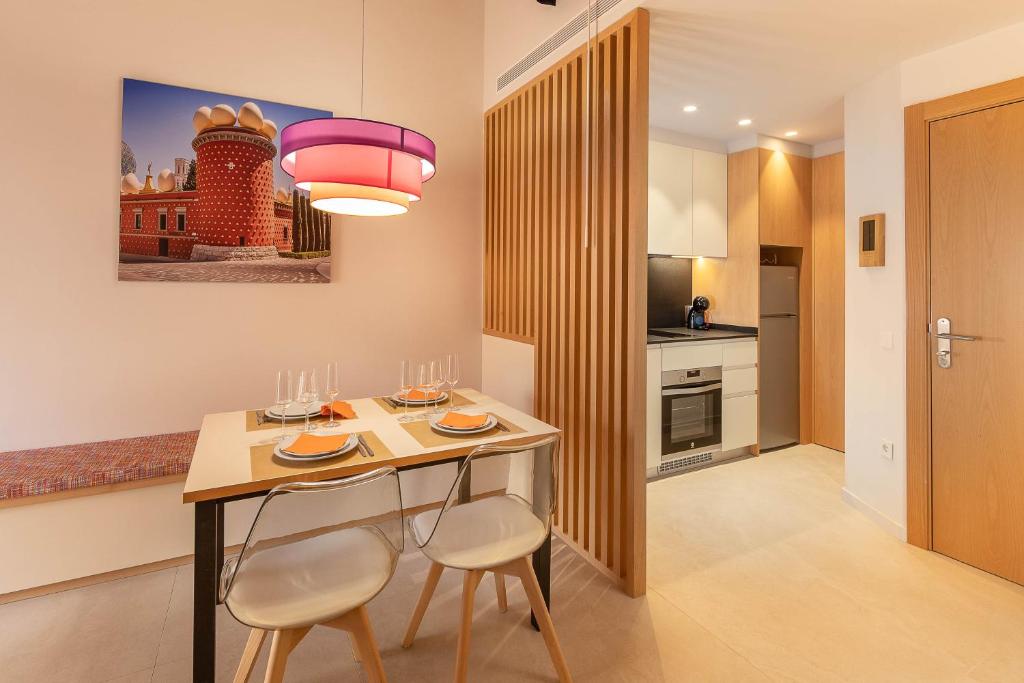 菲格拉斯C&C Apartments的厨房配有带2把椅子的桌子和粉红色的灯