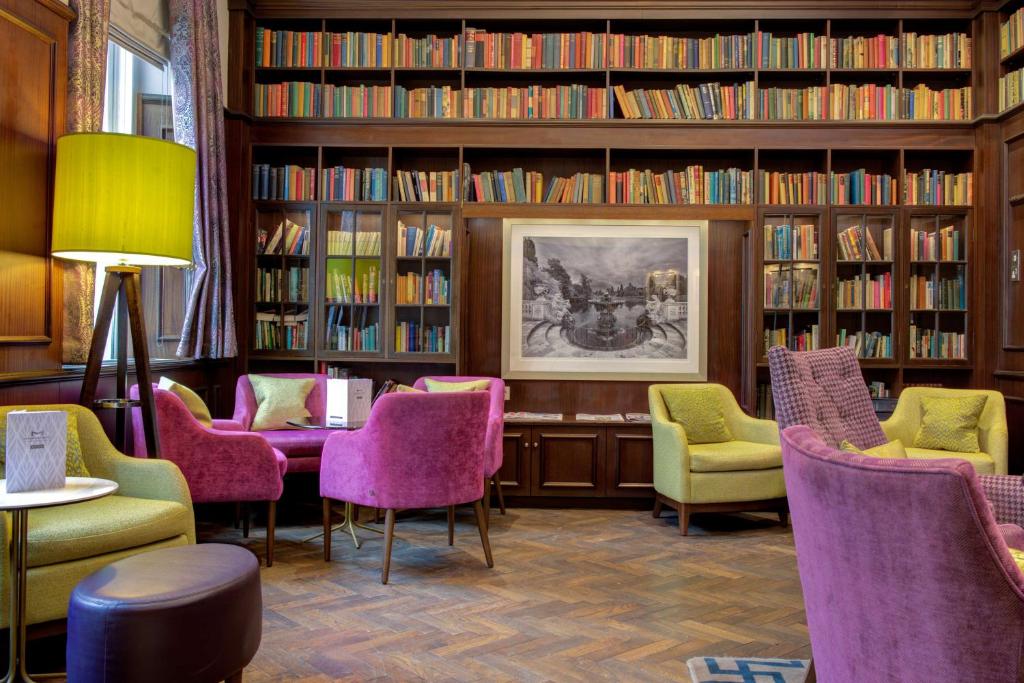 伦敦莫宁海德公园贝斯特韦斯特酒店的图书馆配有紫色椅子和书架