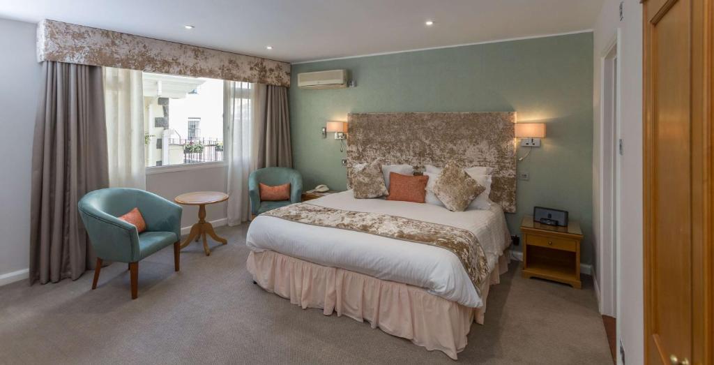 圣彼得港Best Western Moores Central Hotel的配有一张床和一把椅子的酒店客房