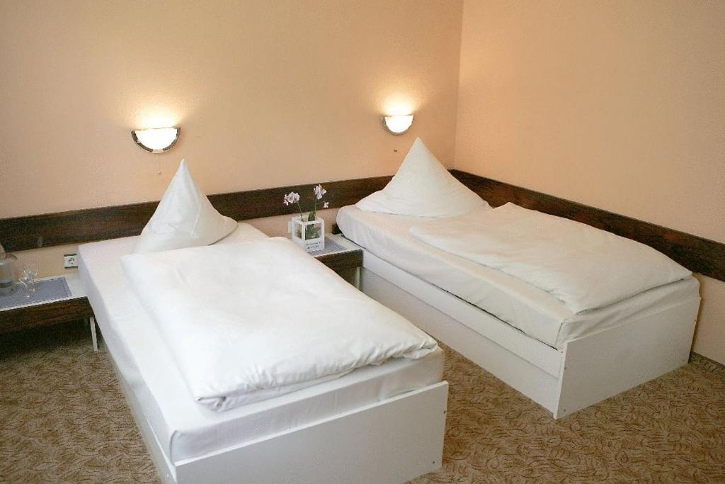 沙肯多夫Rasthaus Hotel Schackendorf的配有白色床单的酒店客房内的两张床